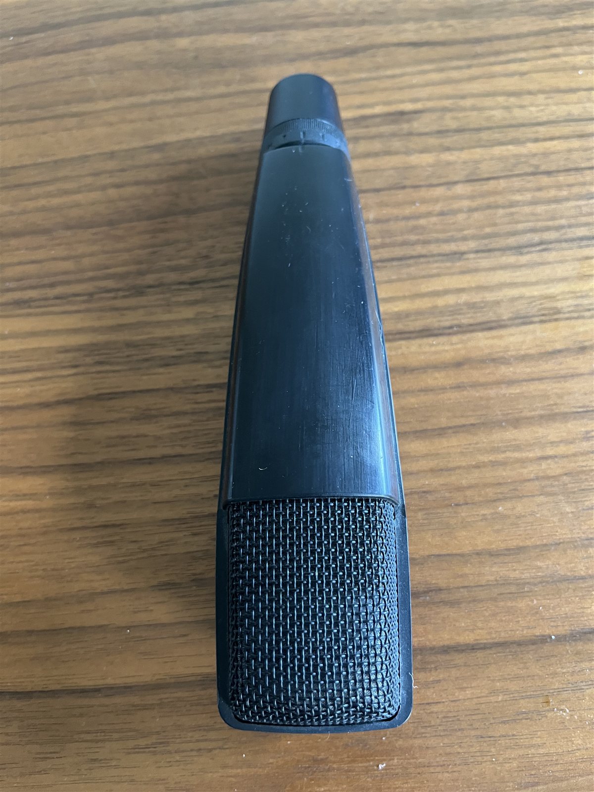 Side view of a studio microphone grille and body.